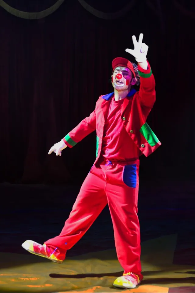 Clown Rudi in rotem Anzug winkt dem Publikum zu