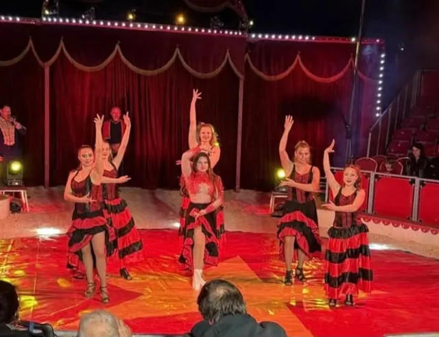 Sechs Tänzerinnen in rot-schwarzen Flamencokleidern in der Manege