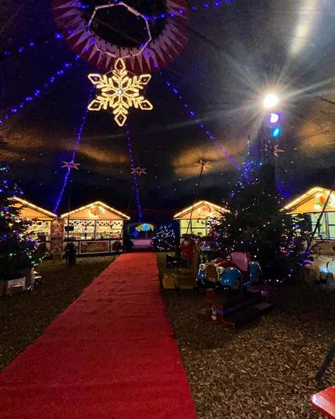Roter Teppich zwischen beleuchteten Weihnachtsmarkthütten und Tannenbäumen, darüber ein leuchtender Schneestern